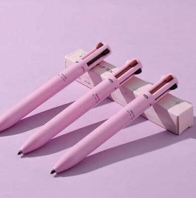 Trois stylos de maquillage 4 en 1 roses sur fond violet, combinant élégance et fonctionnalité.
